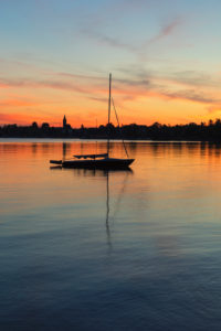 Segelboot bei Sonnenuntergang auf dem Chiemsee, Riemsting, Oberbayern, Deutschland Segelboot bei Sonnenuntergang auf dem Chiemsee, Riemsting, Oberbayern, Deutschland