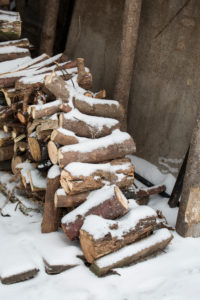 snow covered pile of firewood in front of a barn snow covered pile of firewood in front of a barn