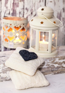 A rustic winter or Christmas deocoration in a white interior, with lanterns, felt heart and knitted deocor objects A rustic winter or Christmas deocoration in a white interior, with lanterns, felt heart and knitted deocor objects