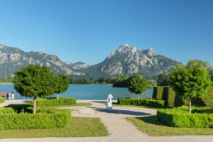 Park am Festspielhaus mit Blick über den Forgensee zu Schloss Hohenschwangau und den Tannheimer Bergen, Allgäu, Schwaben, Oberbayern, Deutschland Park am Festspielhaus mit Blick über den Forgensee zu Schloss Hohenschwangau und den Tannheimer Bergen, Allgäu, Schwaben, Oberbayern, Deutschland