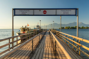 Ausflugsschiffe am Bootsanleger von Gstadt am Chiemsee bei Sonnenaufgang, Fraueninsel hinten, Oberbayern, Deutschland Ausflugsschiffe am Bootsanleger von Gstadt am Chiemsee bei Sonnenaufgang, Fraueninsel hinten, Oberbayern, Deutschland