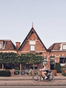 2 female cyclists ride past a residential building, Leiden, Netherlands 2 female cyclists ride past a residential building, Leiden, Netherlands