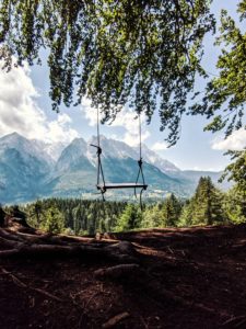 Swing hangs on a tree, view of the Zugspitze and the Wetterstein massif Swing hangs on a tree, view of the Zugspitze and the Wetterstein massif