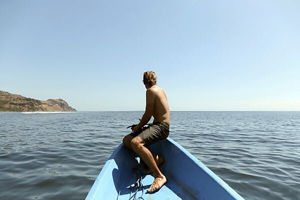 Senior man sitting on the beach in a deck chair with a fishing rod -  SuperStock