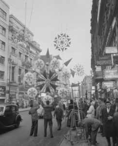 1930s BUSY LEXINGTON AVENUE TRAFFIC AND BLOOMINGDALES STORE WITH FLAGS  PEDESTRIAN SHOPPERS AT 59TH STREET NEW YORK CITY USA - SuperStock