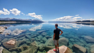 New Zealand, person on crystal blue water overlooking Mount Cook New Zealand, person on crystal blue water overlooking Mount Cook