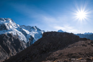Hiker in Mt Cook National Park triumphs on a rock, Mt Cook, Canterbury, New Zealand Hiker in Mt Cook National Park triumphs on a rock, Mt Cook, Canterbury, New Zealand