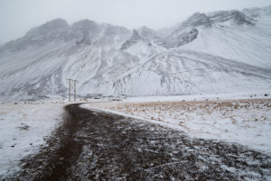 Snowy mountain landscape with gravel road and electricity pylon in the fog, Höfn, Austurland, Iceland Snowy mountain landscape with gravel road and electricity pylon in the fog, Höfn, Austurland, Iceland