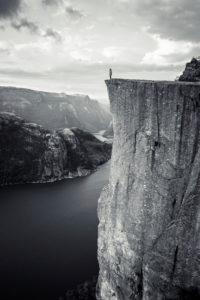 Person on the cliff of Preikestolen looks out over the Lysefjord, Rogaland, Norway Person on the cliff of Preikestolen looks out over the Lysefjord, Rogaland, Norway