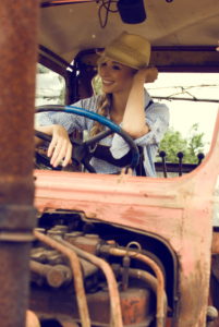 Blond woman, leather pants, checkered blouse, hat, tractor, old, sitting, happy, smiling, Blond woman, leather pants, checkered blouse, hat, tractor, old, sitting, happy, smiling,