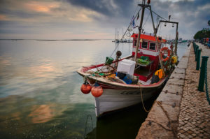 Europe, Portugal, Algarve, Litoral, Sotavento, Faro District, Olhao, Avenida 5 de Outubro, promenade at the market halls, fishing boat at sunset Europe, Portugal, Algarve, Litoral, Sotavento, Faro District, Olhao, Avenida 5 de Outubro, promenade at the market halls, fishing boat at sunset