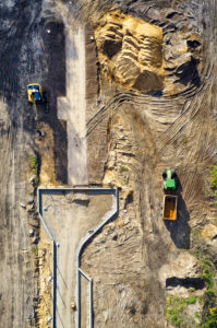 Infrastruktur, Erschließung eines Baugebiets, Erdbewegung, verschiedene Bodenarten werden sichtbar, Baufahrzeuge, Baulinien, Straßenführung, Hochformat Infrastruktur, Erschließung eines Baugebiets, Erdbewegung, verschiedene Bodenarten werden sichtbar, Baufahrzeuge, Baulinien, Straßenführung, Hochformat