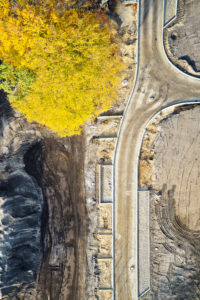 Infrastructure, structures, shapes, traces, earth colors, yellow tree top, development of a building area, road layout, single tree in the street area, portrait format Infrastructure, structures, shapes, traces, earth colors, yellow tree top, development of a building area, road layout, single tree in the street area, portrait format