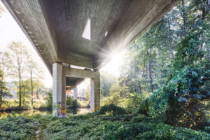 Architecture, technology and nature, under a bridge, superstructure in the back light, sun spot with rays of light, concrete bridge over the Ilmenau and a railway area Architecture, technology and nature, under a bridge, superstructure in the back light, sun spot with rays of light, concrete bridge over the Ilmenau and a railway area