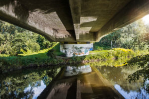 Architecture, technology and nature, under a bridge, bridgehead, superstructure with reflection in the water, concrete bridge over the Ilmenau, historic towpath between Lüneburg and Bardowick Architecture, technology and nature, under a bridge, bridgehead, superstructure with reflection in the water, concrete bridge over the Ilmenau, historic towpath between Lüneburg and Bardowick