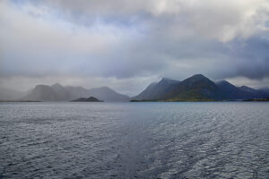 Cruise along the coast of Norway, fog and clouds over the sea and coastal mountains, silhouette of the Vesterålen archipelago