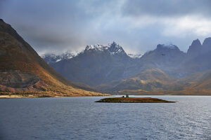 Cruise on the coast of Norway, clouds over snow-covered mountain peaks, silhouette of the Vesterålen archipelago, small island with signal tower