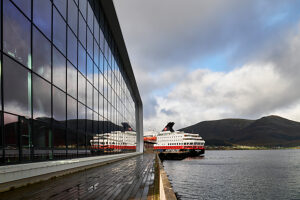 Cruise on the coast of Norway, cruise ship in the harbor of Stokmarknes reflected in the glass facade of the Hurtigruten Museum