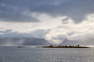 Cruise along the coast of Norway, fog over the open sea between Vesterålen and Lofoten, silvery water and tiny islands with individual trees