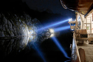 Cruise on the coast of Norway, Lofoten archipelago, narrow channel in the Trollfjord at night, illumination with on-board spotlights