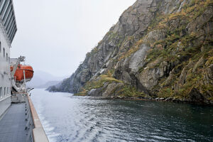 Cruise on the coast of Norway, Lofoten archipelago, narrow channel in the Trollfjord, ship comes close to steep rock faces, orange lifeboat