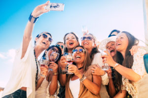 Friends people in group have fun together in friendship celebration party with red wine and selfie picture from phone - joy and happiness for young and senior women - blue sky in background Friends people in group have fun together in friendship celebration party with red wine and selfie picture from phone - joy and happiness for young and senior women - blue sky in background