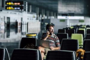 Lonely man sit down and use technology device like laptop and mobile phone at the airport gate waiting for his filght - concept of flights deleted and wait people - rights travel Lonely man sit down and use technology device like laptop and mobile phone at the airport gate waiting for his filght - concept of flights deleted and wait people - rights travel