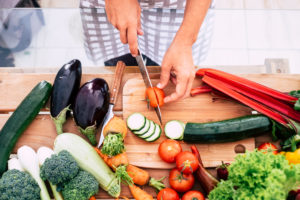 closeup of table full of vegetables like tomatoes, carrots and more - adult or senior cutting food inthe kitchen at home or restaurant - vegan and vegetarian lifestyle and diet closeup of table full of vegetables like tomatoes, carrots and more - adult or senior cutting food inthe kitchen at home or restaurant - vegan and vegetarian lifestyle and diet