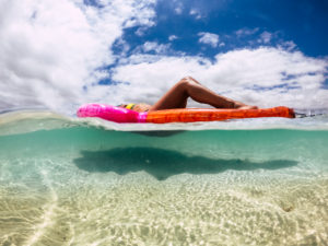 Concept of travel and summer holiday vacation with underwater and out picture of beautiful body woman having a sunbath on a trendy coloured lilo inflatable mattress with nice blue water and sand beach around Concept of travel and summer holiday vacation with underwater and out picture of beautiful body woman having a sunbath on a trendy coloured lilo inflatable mattress with nice blue water and sand beach around