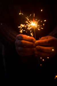 Christmas and new year eve concept image with close up of a pair of man hands taking a red fire sparkler to celebrate the night party - focus on fireworks and hope for people future Christmas and new year eve concept image with close up of a pair of man hands taking a red fire sparkler to celebrate the night party - focus on fireworks and hope for people future