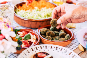 Close up of man taking polpetta in vegetarian food table - concept of market and catering restaurant for party or event Close up of man taking polpetta in vegetarian food table - concept of market and catering restaurant for party or event