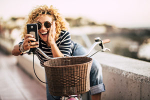 Cheerful happy beautiful curly trendy woman taking selfie picture with modern phone - people enjoying the outdoor technology leisure activity - defocused beautiful background Cheerful happy beautiful curly trendy woman taking selfie picture with modern phone - people enjoying the outdoor technology leisure activity - defocused beautiful background