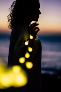 Silhouette of a woman holding a glowing string of lights, evening mood Silhouette of a woman holding a glowing string of lights, evening mood