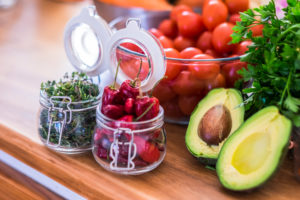 Healthy food with vegetables and fruit cloured on a wooden table - vegan or vegetarian nutrition concept - guacamole avocado trendy lifestyle health with tomatoes and red chilly pepper Healthy food with vegetables and fruit cloured on a wooden table - vegan or vegetarian nutrition concept - guacamole avocado trendy lifestyle health with tomatoes and red chilly pepper