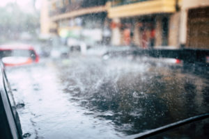 Close up of black new car roof with heavy rain on it - bad weather forcast in the city in winter season - damage insurance concept Close up of black new car roof with heavy rain on it - bad weather forcast in the city in winter season - damage insurance concept