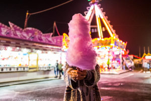 Hidden woman with pink strawberry cotton candy at night luna park - people have fun in nightlife at the event in the city Hidden woman with pink strawberry cotton candy at night luna park - people have fun in nightlife at the event in the city