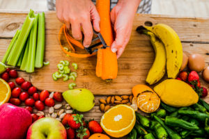 Close up of woman adult hands cutting fresh seasonal healthy carrot and mixed vegetables for health lifestyle food and diet weight loss activity at home Close up of woman adult hands cutting fresh seasonal healthy carrot and mixed vegetables for health lifestyle food and diet weight loss activity at home