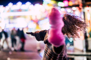 Luna park and nightlife with crazy lady dancing with pink cotton candy and coloured bonek lights in background Luna park and nightlife with crazy lady dancing with pink cotton candy and coloured bonek lights in background