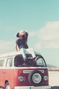 Love and travel with romantic wanderlust young people couple kiss and stay together on an old vintage van rooftop enjoying romance and relationship - drive vehicle and move Love and travel with romantic wanderlust young people couple kiss and stay together on an old vintage van rooftop enjoying romance and relationship - drive vehicle and move