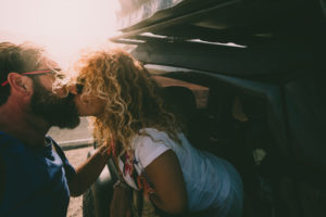 Adult couple in love kiss outside the car and travel together - concept of free and happy lifestyle for beautiful people traveling and enjoying life Adult couple in love kiss outside the car and travel together - concept of free and happy lifestyle for beautiful people traveling and enjoying life