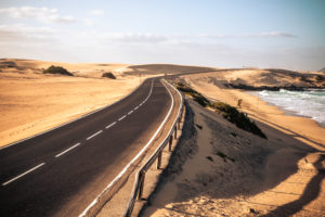 Long black asphalt road with desert and beach around for travel and adventure summer lifestyle concept with nobody traveling and no traffic cars - beautifful adventure places to discover Long black asphalt road with desert and beach around for travel and adventure summer lifestyle concept with nobody traveling and no traffic cars - beautifful adventure places to discover