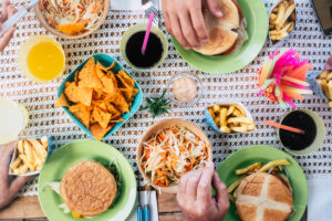 Vertical table view with people eating junk hamburger food together - home scene and friendship at lunch concept Vertical table view with people eating junk hamburger food together - home scene and friendship at lunch concept