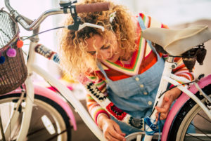 Happy adult woman at home in hobby work leisure activity indoor modify a female bike with piece of covers and full of colors - creativity concept and hippy boho bicycle creation - people enjoying artistic job at home Happy adult woman at home in hobby work leisure activity indoor modify a female bike with piece of covers and full of colors - creativity concept and hippy boho bicycle creation - people enjoying artistic job at home