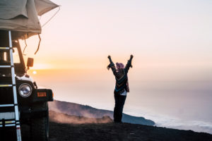 Happy joy people travel with car and tent roof in wild places enjoying the sunset on the top of a mountain - travel and freedom lifestyle concept for young woman Happy joy people travel with car and tent roof in wild places enjoying the sunset on the top of a mountain - travel and freedom lifestyle concept for young woman