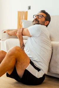 An adult man performing a full-body workout at home with gym equipment, focusing on strength training exercises, warm-ups, flexibility, and balancing activities to maintain overall fitness and health