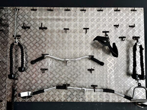 Gym equipment neatly organized on a metallic wall, featuring a variety of weights, dumbbells, resistance tools, and fitness accessories, designed for strength training and promoting physical wellness