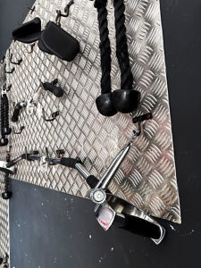 Metallic wall in a fitness center featuring weights, dumbbells, and a range of workout tools neatly organized for efficient strength training and resistance exercise programs