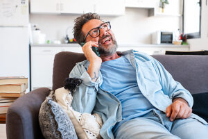 One adult man alone at home enjoying call communication on smartphone mobile phone device gesturing with hands and smiling happy. Modern people indoor leisure activity. Mature male calling online