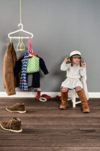 Girl sits on a chair in the wardrobe and wears the shoes of the mother,