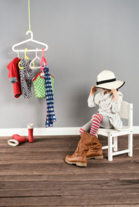Girl sits on a chair in the wardrobe and wears the shoes of the mother,